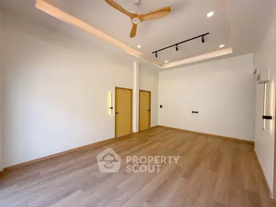 Spacious modern living room with wooden flooring and ceiling fan, perfect for comfortable living.