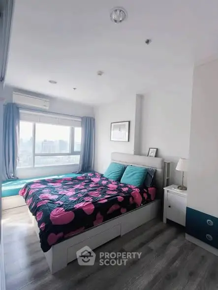 Modern bedroom with large window and stylish decor in urban apartment.