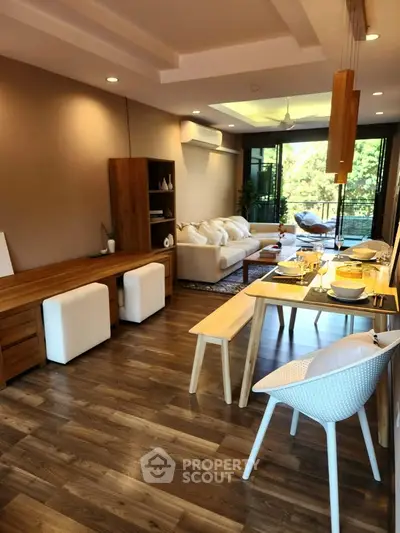 Spacious living room with elegant dining area and large windows overlooking greenery.