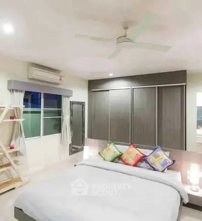 Modern bedroom with stylish decor, ceiling fan, and large window for natural light.