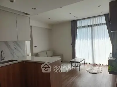 Modern open-plan living room with kitchen, featuring large windows and stylish decor.