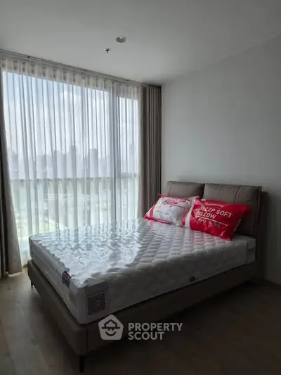 Modern bedroom with large window and stylish bed in a high-rise apartment.