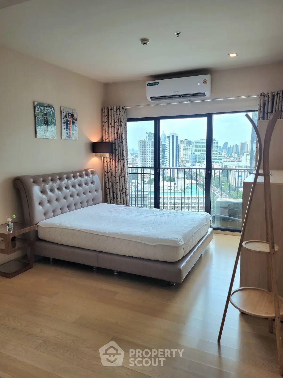 Spacious bedroom with city view and modern furnishings in high-rise apartment