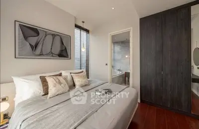 Elegant bedroom with modern decor and ensuite bathroom, featuring cozy bedding and stylish artwork.