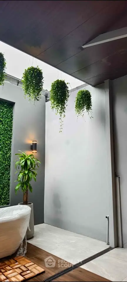 Modern outdoor space with hanging plants and stylish bathtub, perfect for relaxation and luxury living.