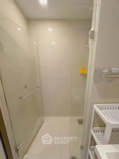 Modern bathroom with glass shower enclosure and sleek white shelving.