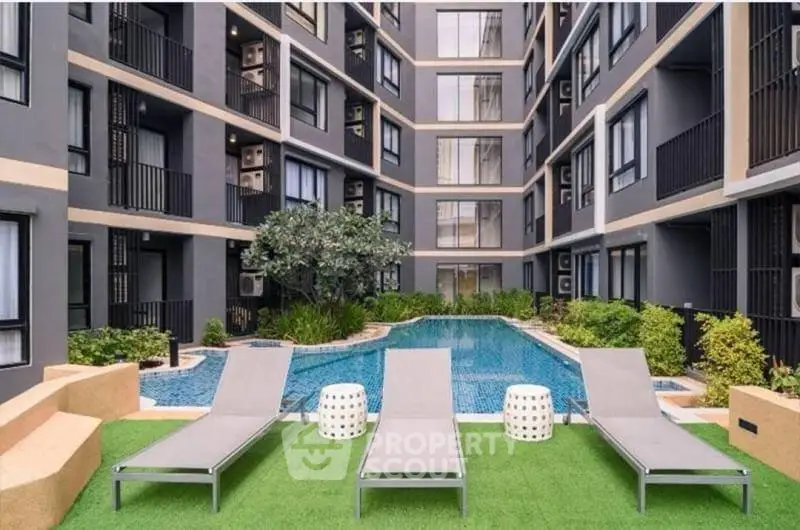 Modern apartment complex with pool and lounge chairs, perfect for relaxation and urban living.