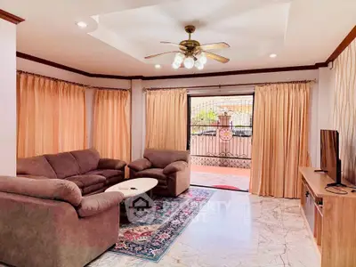 Spacious living room with cozy seating and elegant decor, featuring a ceiling fan and natural light.