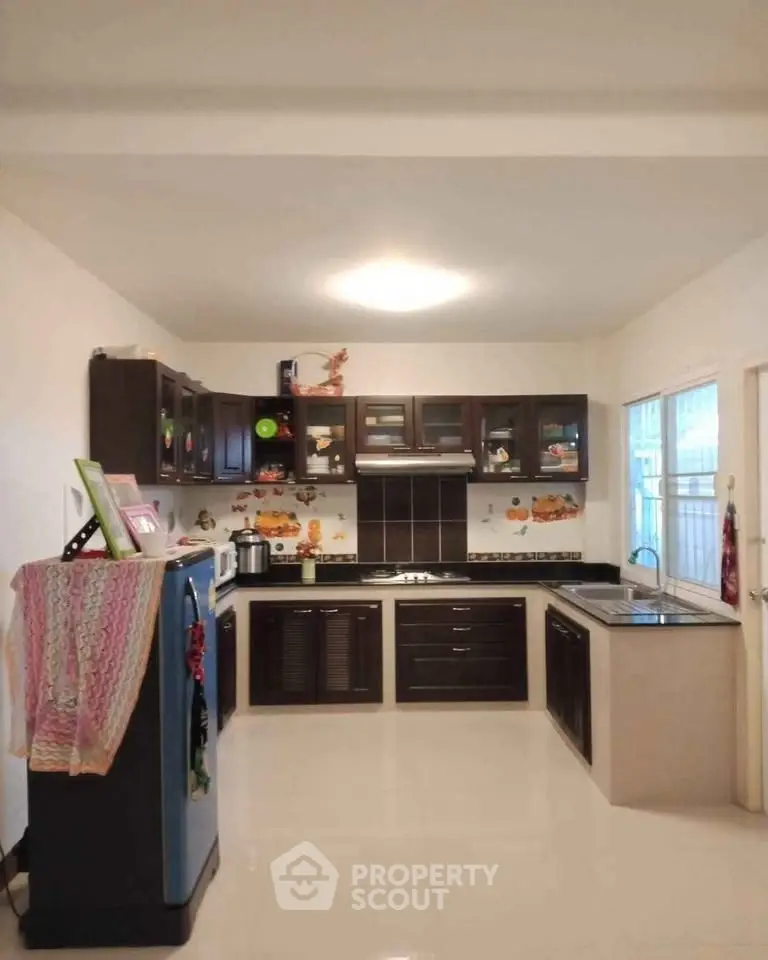 Spacious kitchen with modern dark wood cabinets and sleek countertops.