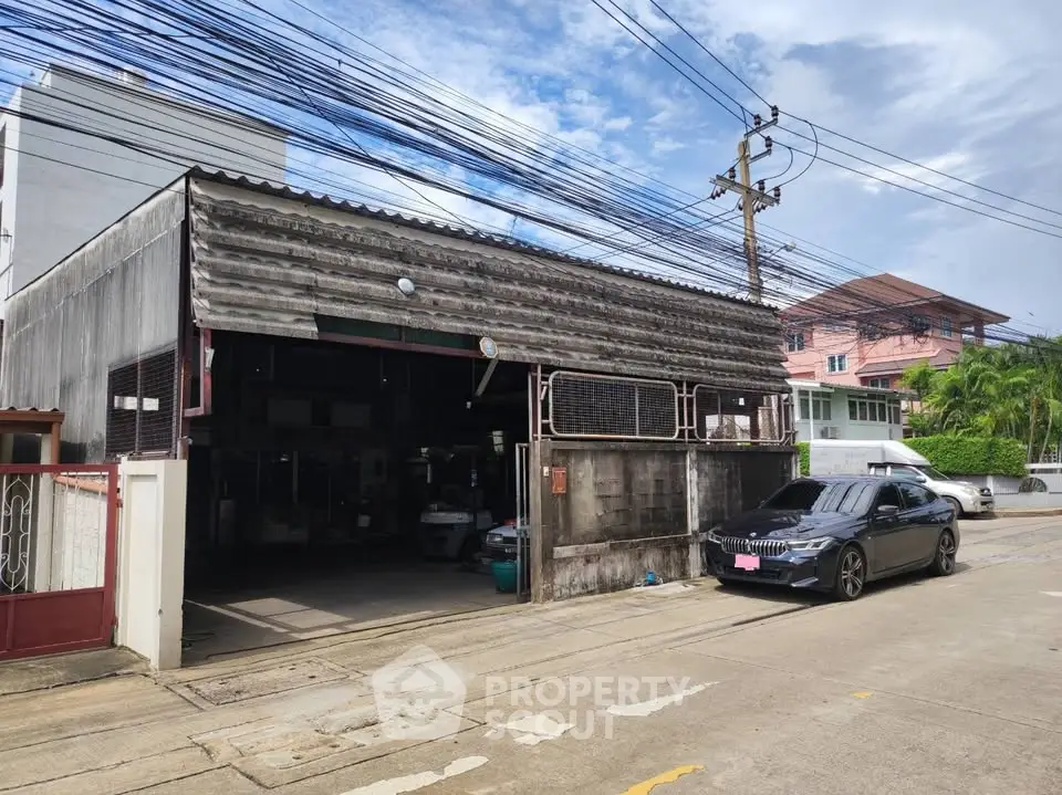 Industrial-style warehouse with street view and parked car, ideal for commercial use.