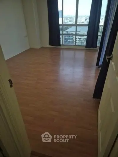 Spacious empty room with large window and city view, perfect for customization.