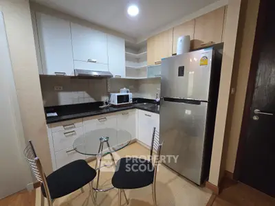 Modern kitchen with sleek appliances and cozy dining area in stylish apartment.