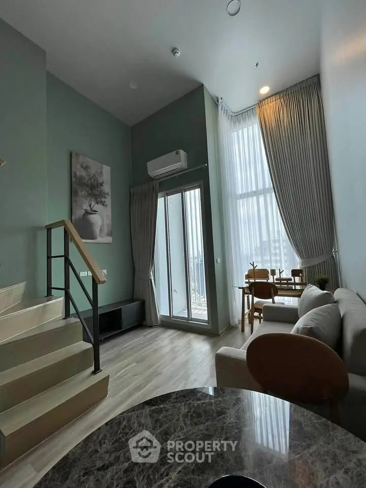 Modern living room with high ceilings, large windows, and stylish decor in a contemporary apartment.