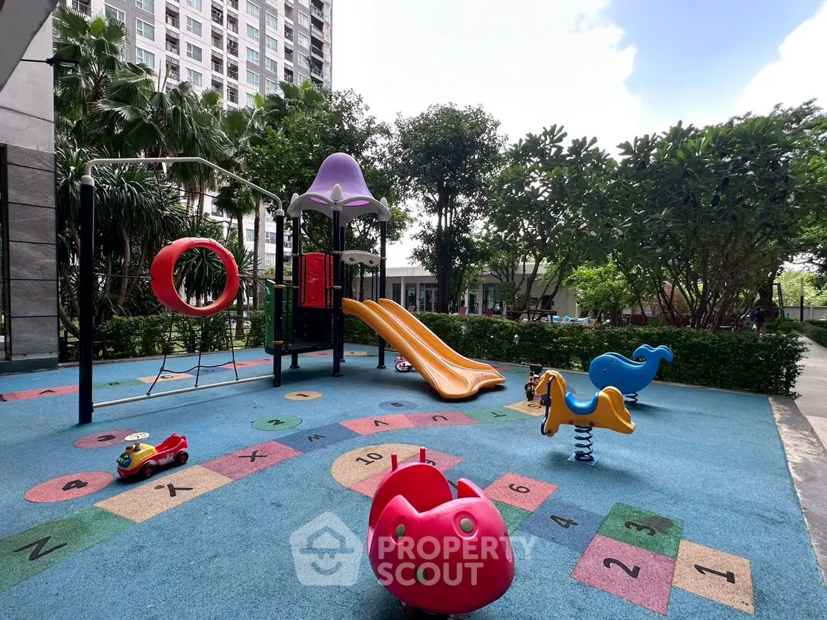 Vibrant playground in modern residential complex with colorful slides and lush greenery.