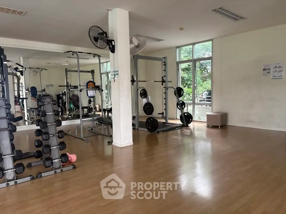 Spacious gym with modern equipment and large windows for natural light.