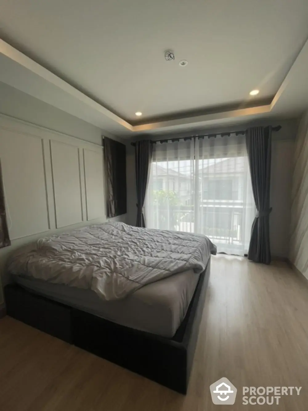 Spacious bedroom with modern design, large bed, elegant dark curtains, and ample natural light from floor-to-ceiling windows, perfect for a restful retreat.