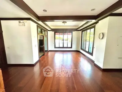 Spacious living room with wooden flooring and large windows offering natural light.