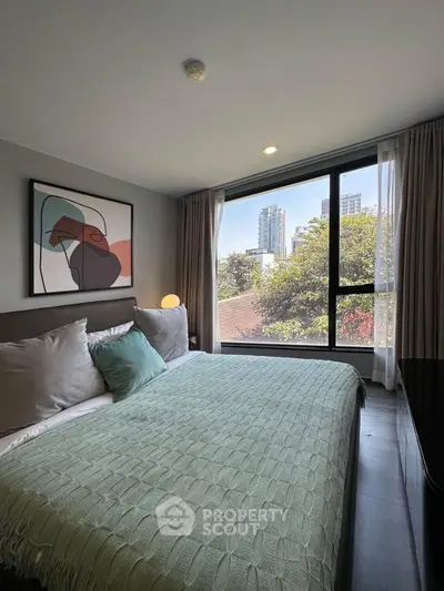 Modern bedroom with large window offering city view, stylish decor, and cozy bedding.