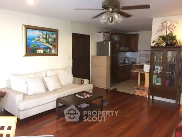 Charming living room with hardwood floors, cozy sofa, and open kitchen layout in a modern apartment.