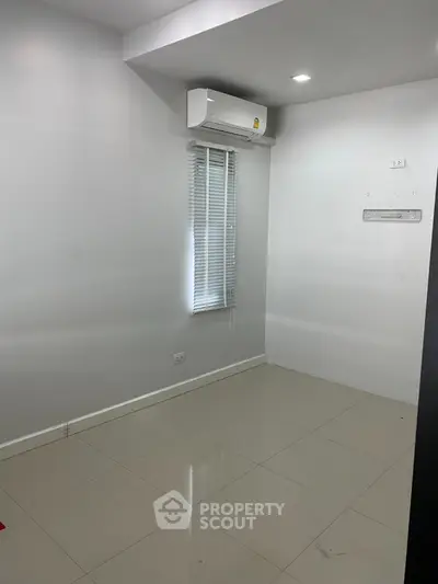 Minimalist empty room with air conditioning and tiled floor, ready for customization.