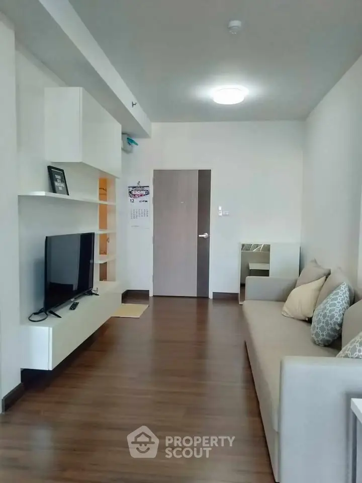 Modern living room with sleek design, featuring a comfortable sofa and wall-mounted TV, perfect for relaxation.