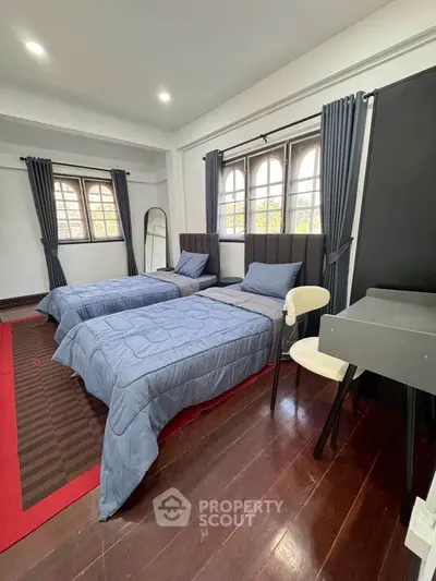 Charming bedroom with twin beds, elegant decor, and ample natural light from large windows.