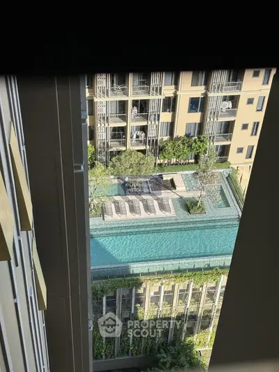 Stunning aerial view of modern apartment complex with rooftop pool and lush greenery.