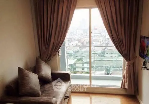 Cozy living room with city view from balcony, featuring elegant curtains and comfortable seating.