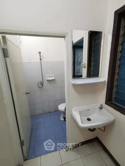 Compact bathroom with shower, sink, and toilet in a minimalist design.