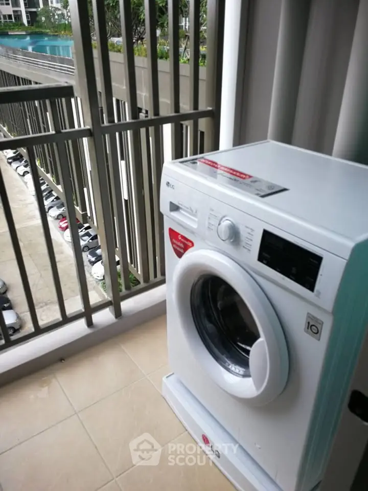 Modern apartment balcony with washing machine and pool view, ideal for urban living.