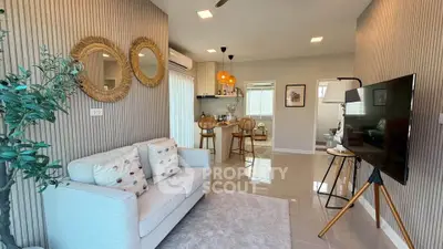 Modern living room with stylish decor and open kitchen layout, featuring cozy seating and elegant lighting.