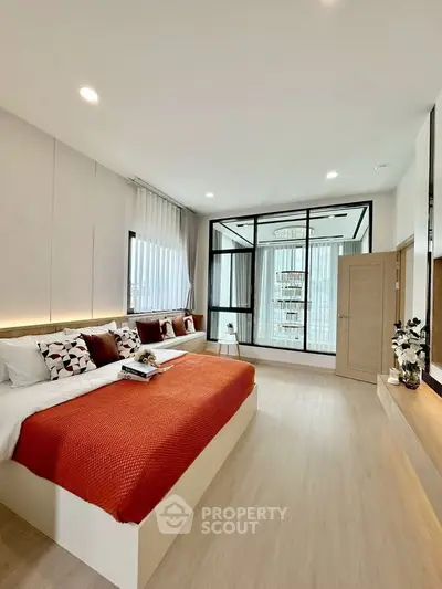 Spacious modern bedroom with elegant decor and large windows for natural light.