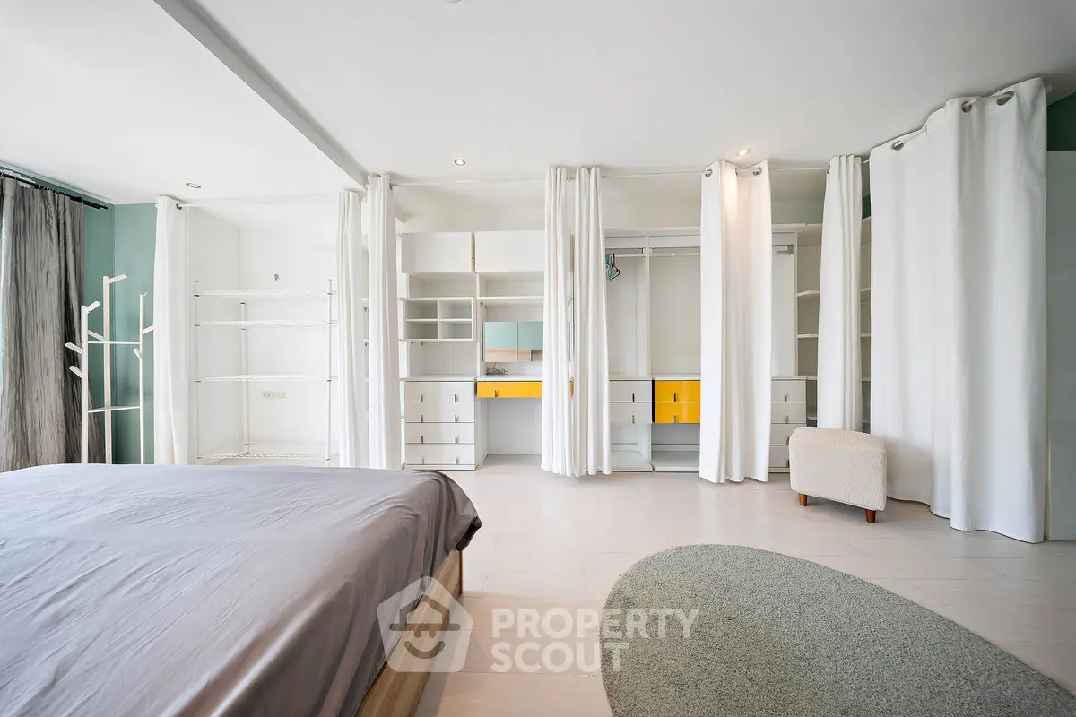 Spacious modern bedroom with open walk-in closet and minimalist design.