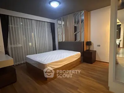 Spacious modern bedroom with elegant decor and large window for natural light.