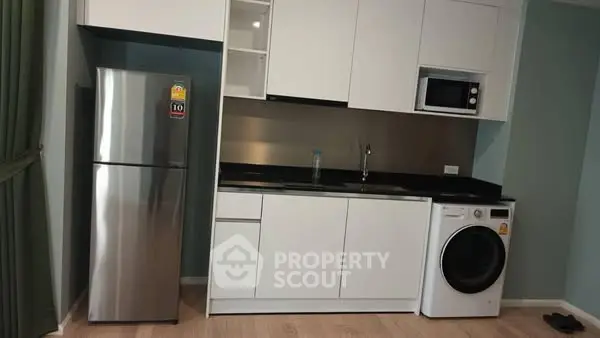 Modern kitchen with sleek appliances including fridge, microwave, and washing machine.