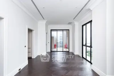 Spacious modern living room with elegant hardwood floors and large windows offering abundant natural light.