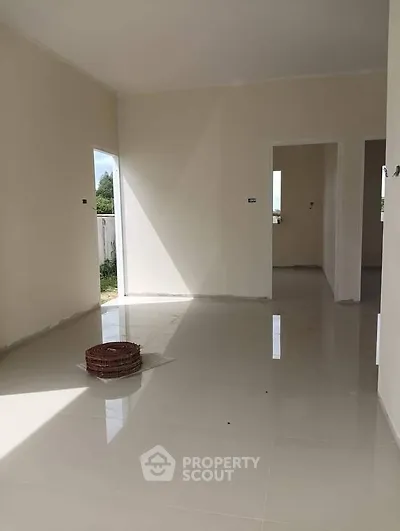 Spacious unfurnished room with glossy tiled floors and natural light.