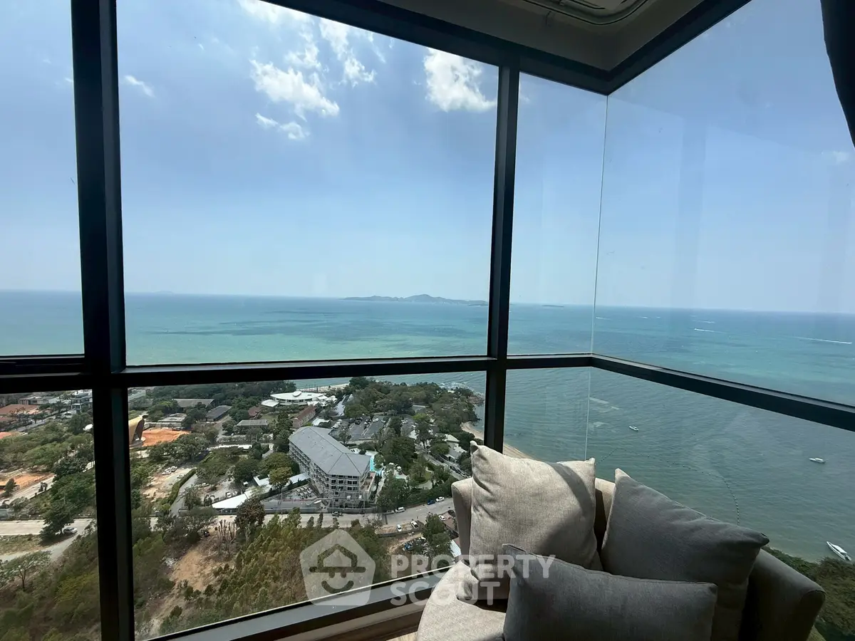 Stunning corner unit with panoramic ocean view from high-rise building, featuring cozy seating area.