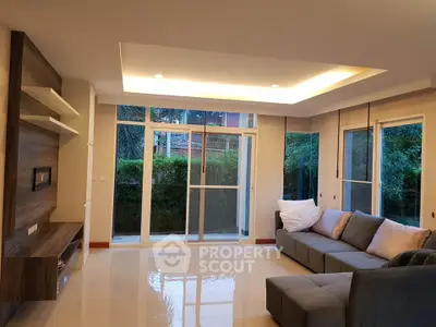 Spacious living room with modern design and large windows overlooking lush greenery.