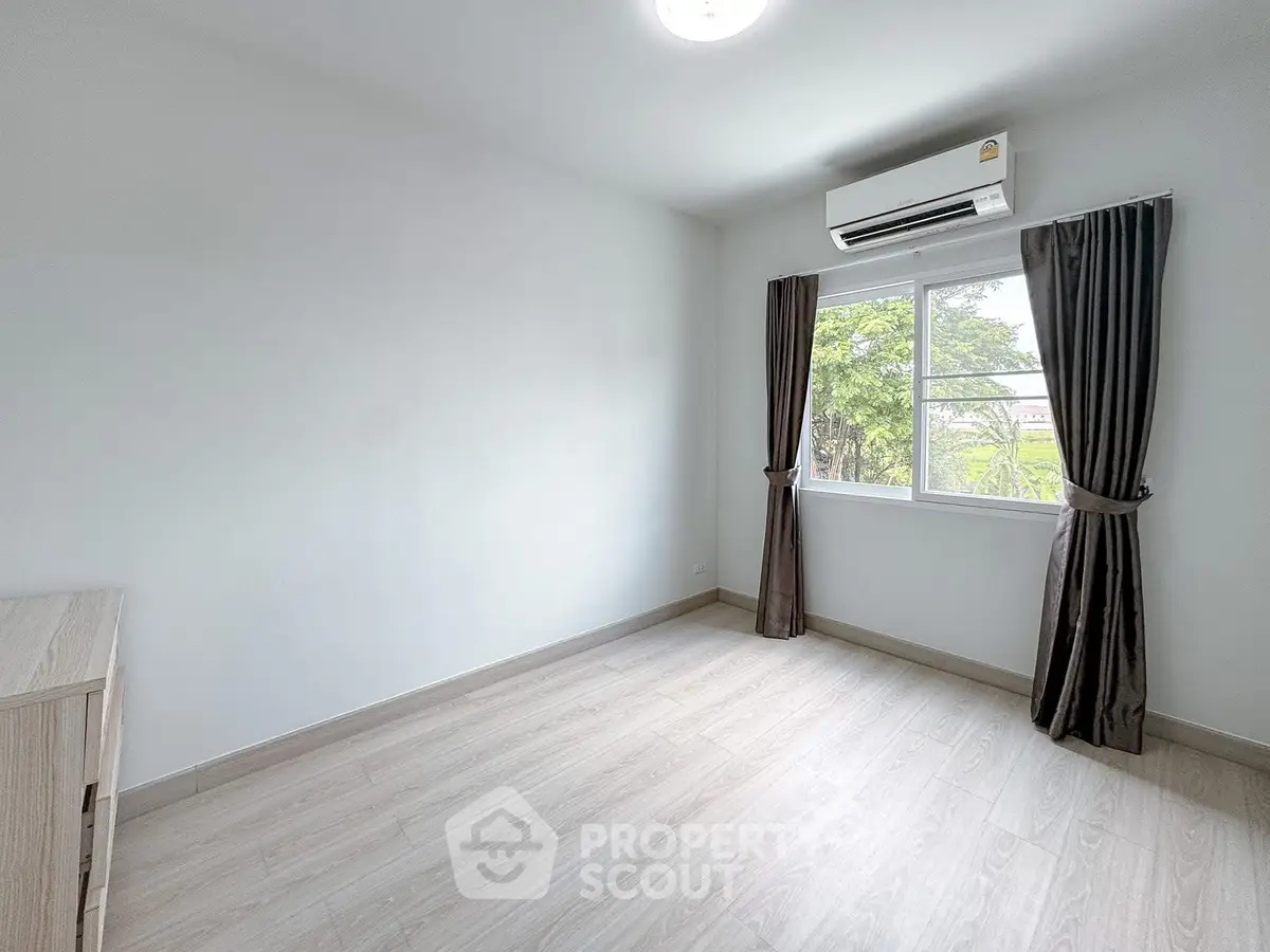 Bright empty bedroom with air conditioning and large window view