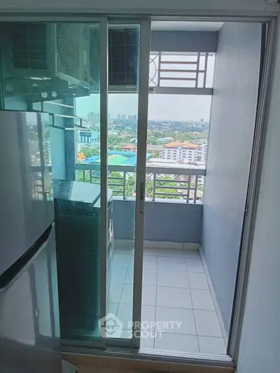 Compact balcony with city view and sliding glass door in modern apartment.