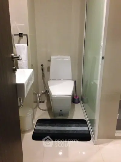Compact modern bathroom with sleek fixtures and glass shower door