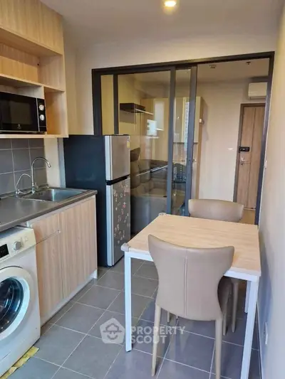 Modern compact kitchen with dining area and washing machine in cozy apartment