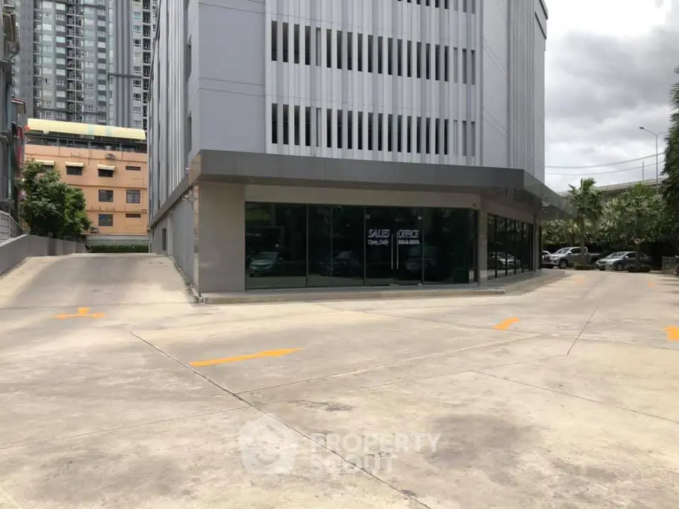 Modern commercial building exterior with large glass windows and spacious parking area.