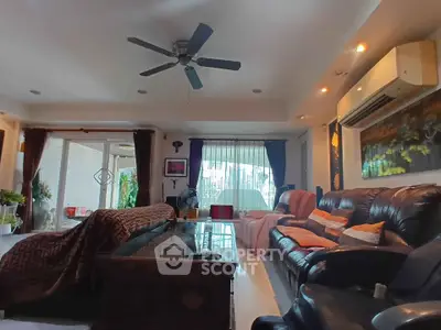 Spacious living room with leather sofas and ceiling fan, perfect for relaxation.