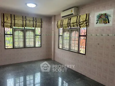 Spacious room with large windows and air conditioning, featuring decorative curtains and tiled walls.