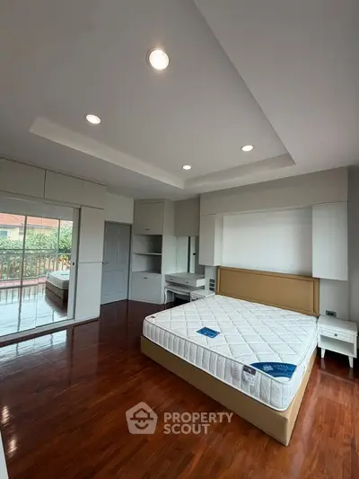 Spacious bedroom with hardwood floors and large windows overlooking a scenic view, featuring modern furniture.