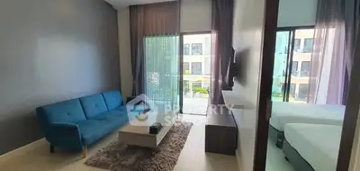 Modern living room with blue sofa and large windows overlooking a serene view.