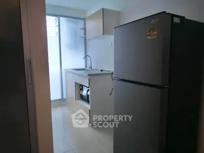 Modern kitchen with sleek fridge and minimalist design in a compact space.