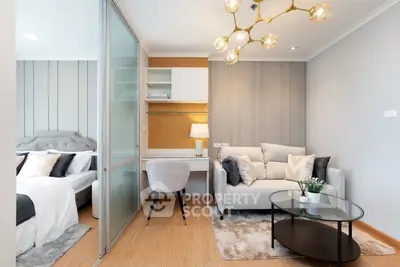 Modern living room with cozy sofa, stylish lighting, and adjacent bedroom in open-plan apartment.